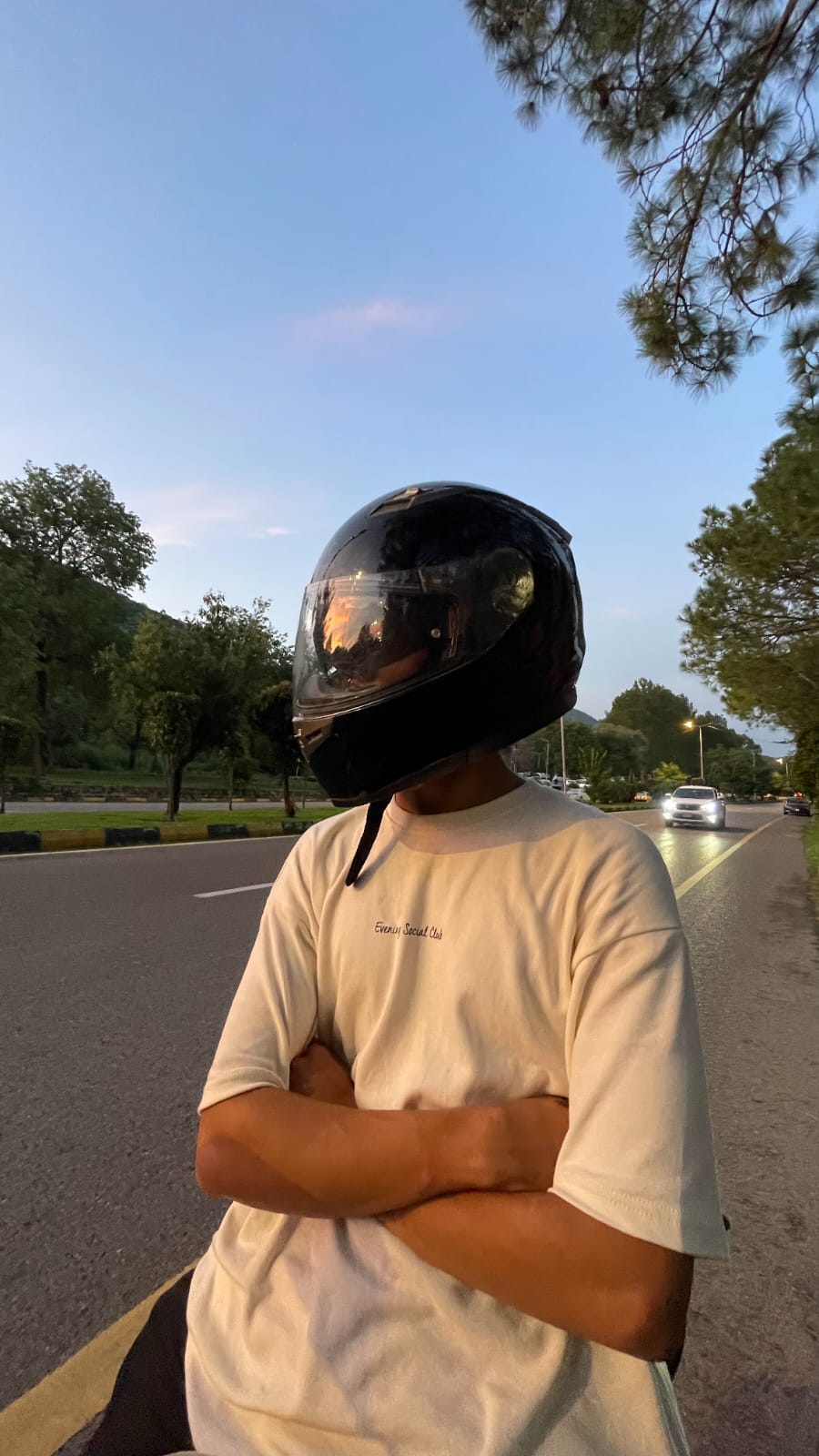 Illiyin wearing a helmet standing on a road at dusk